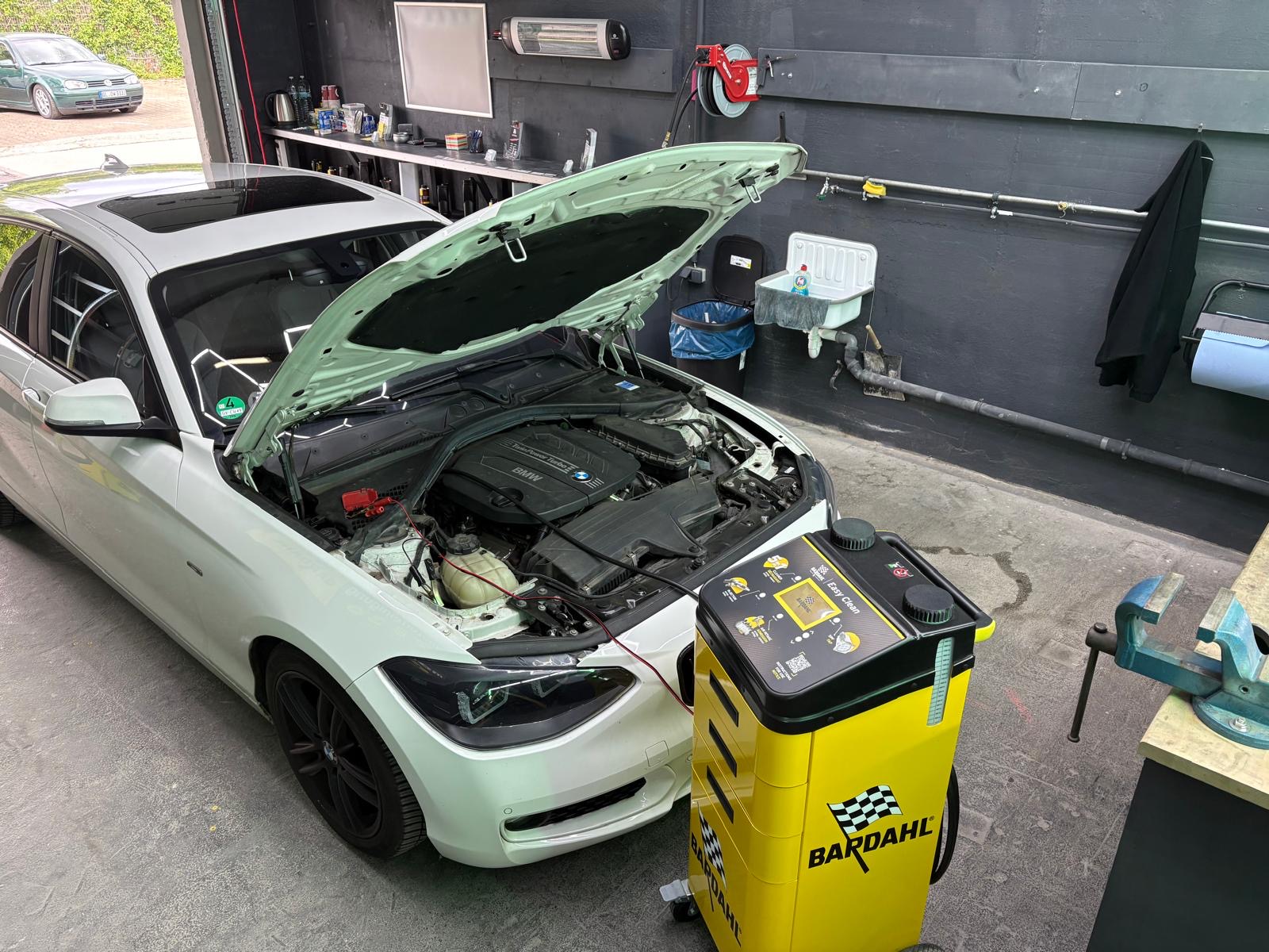 Fahrzeug mit geöffneter Motorhaube und angeschlossenem Bardahl-Reinigungsgerät in der Werkstatt