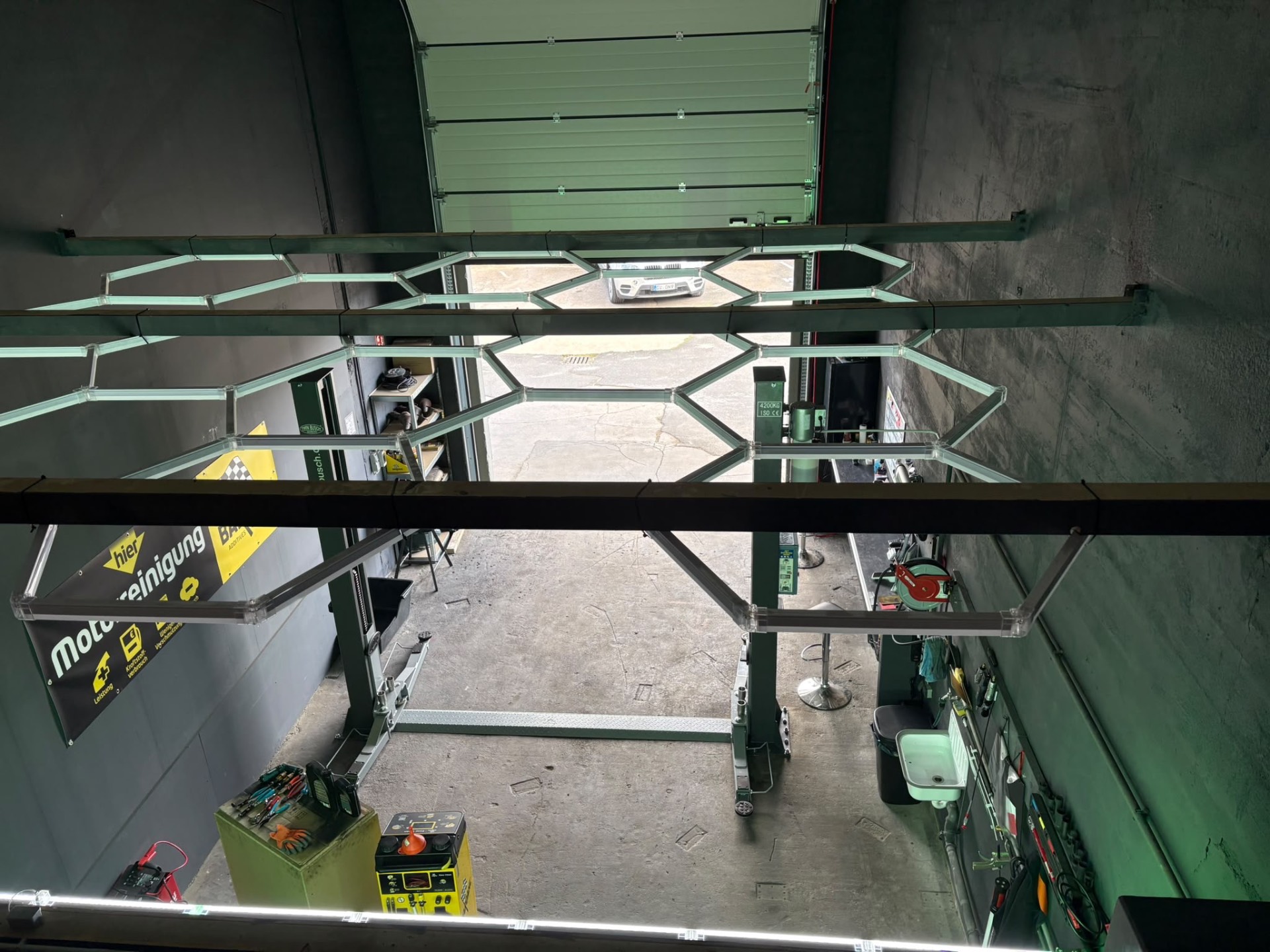 Werkstatthalle von CleanMobil DPF Service mit hexagonaler LED-Beleuchtung und Hebebühne